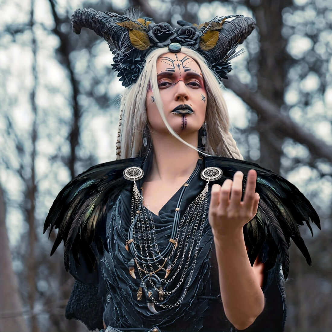 Person in elaborate costume with horns and feathers in a forest setting