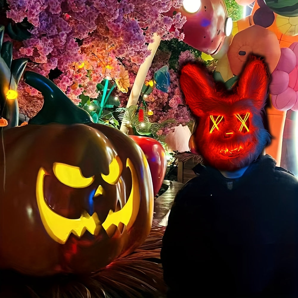 Person wearing a glowing red mask with a carved pumpkin in front of colorful Halloween decorations.
