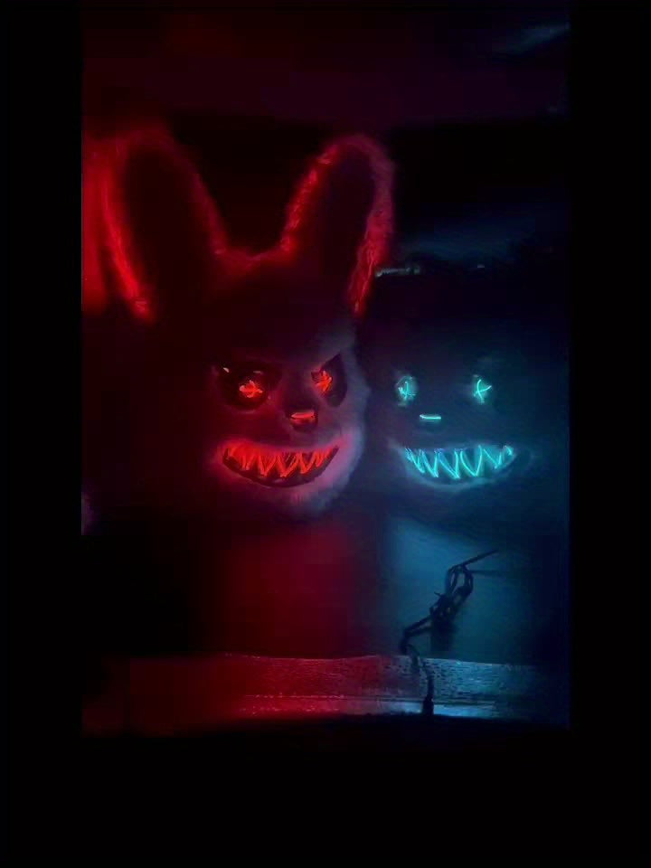 Two glowing masks, one red and one blue, in a dark setting.