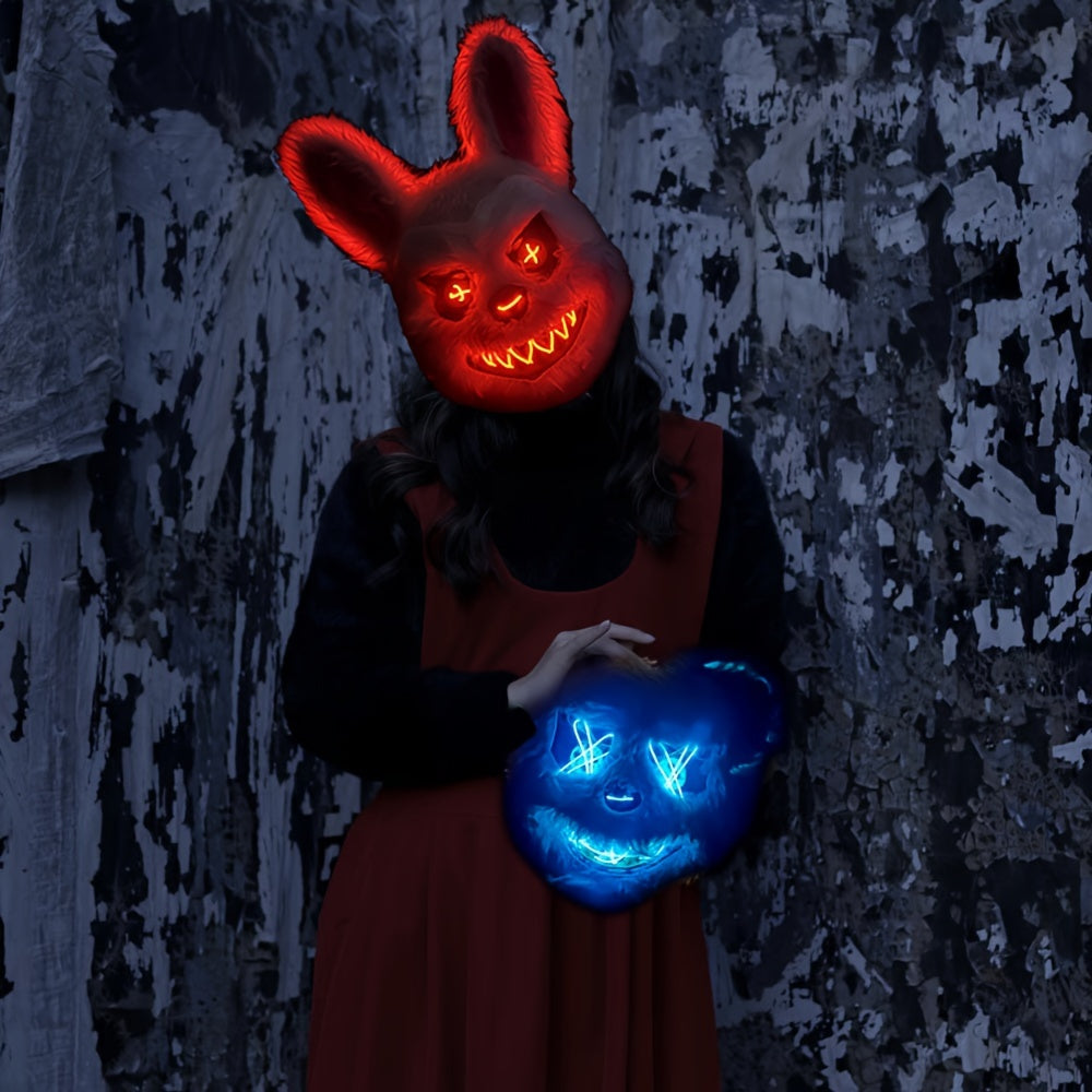 Person wearing a glowing red mask and holding a blue glowing mask against a textured wall.