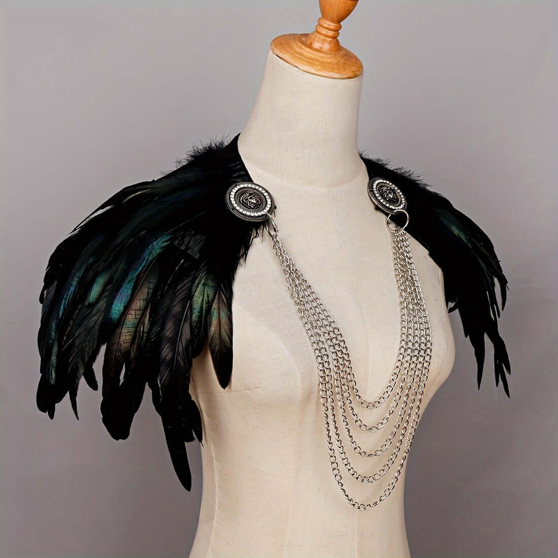 Feathered shoulder piece with chains on a mannequin against a gray background